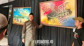 SENANG. Ketua DPRD Sumenep, H. Zainal Arifin, saat menunjukkan lukisan kaligrafi yang beliau beli dari salah satu seniman lukis asal Desa Tenonan, Kecamatan Manding. (doc.Redaksi Linkking.id)