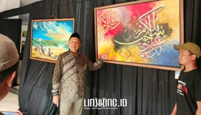 SENANG. Ketua DPRD Sumenep, H. Zainal Arifin, saat menunjukkan lukisan kaligrafi yang beliau beli dari salah satu seniman lukis asal Desa Tenonan, Kecamatan Manding. (doc.Redaksi Linkking.id)