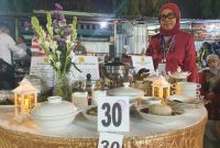 JUARA. Aisyah, Owner Resto Osyfood, berpose di depan meja sajian kuliner saat Madura Culinary Festival 2025 di Taman Bunga Sumenep. (dok.Redaksi Linkking.id)