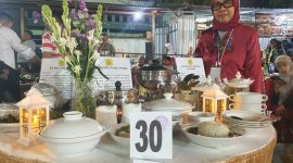 JUARA. Aisyah, Owner Resto Osyfood, berpose di depan meja sajian kuliner saat Madura Culinary Festival 2025 di Taman Bunga Sumenep. (dok.Redaksi Linkking.id)