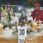JUARA. Aisyah, Owner Resto Osyfood, berpose di depan meja sajian kuliner saat Madura Culinary Festival 2025 di Taman Bunga Sumenep. (dok.Redaksi Linkking.id)